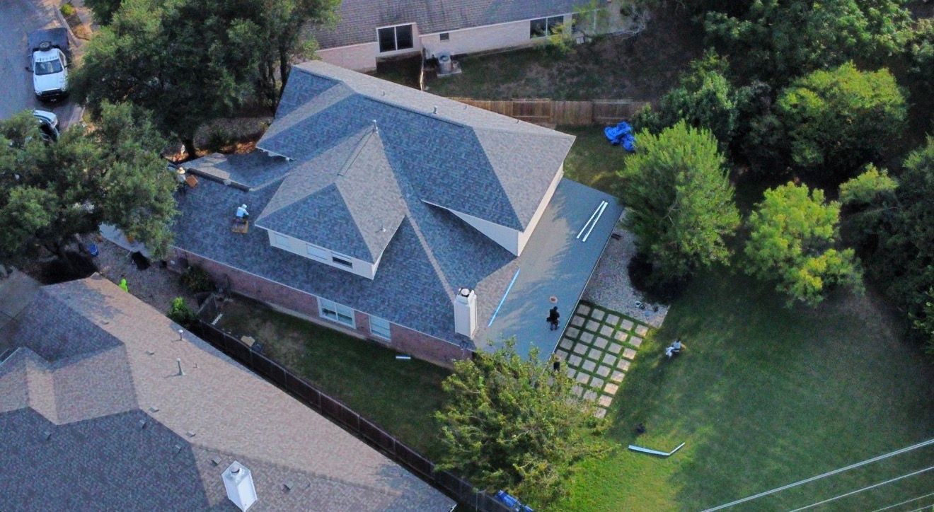 Drone view of a completed blue-gray shingle roof on a residential property