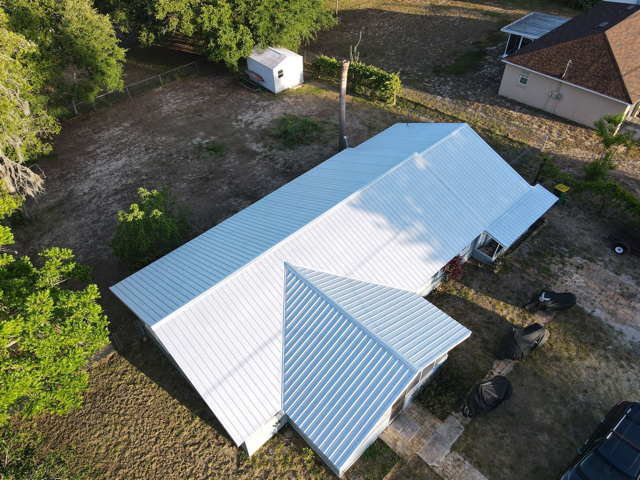 Roofing contractor inspecting metal panels and flashing on an Auburndale, Florida property