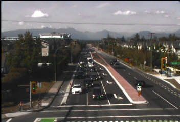 Aerial view of a multi-lane highway with a red bus lane and cars under a cloudy sky.