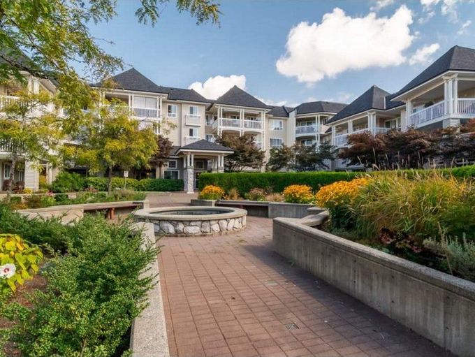Courtyard garden with fountain, flower beds, and townhomes under a blue sky