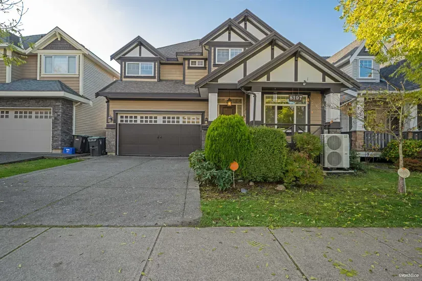 Suburban townhouse with two-car garage, driveway, and front lawn under clear daylight
