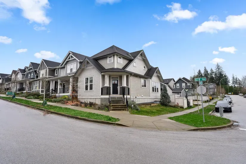 Row of gray townhouses on a corner street under a blue sky