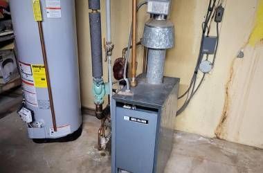 A water heater and a boiler are in a basement.