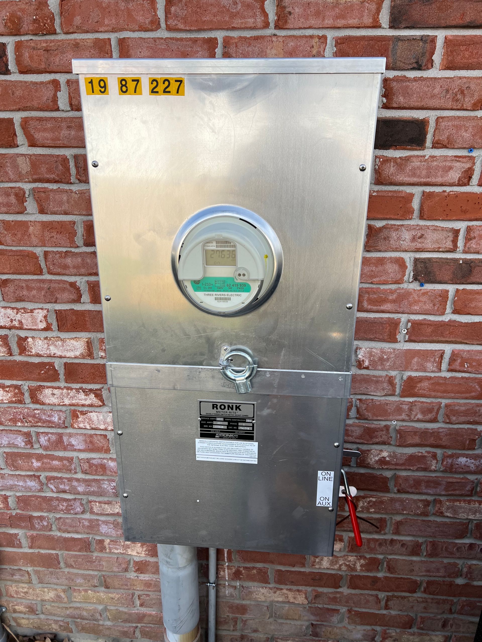 A brick wall with a metal box with a meter on it