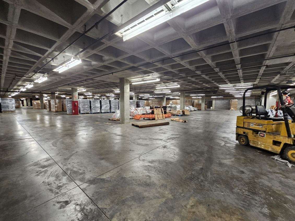 A yellow forklift is moving boxes in a large warehouse.