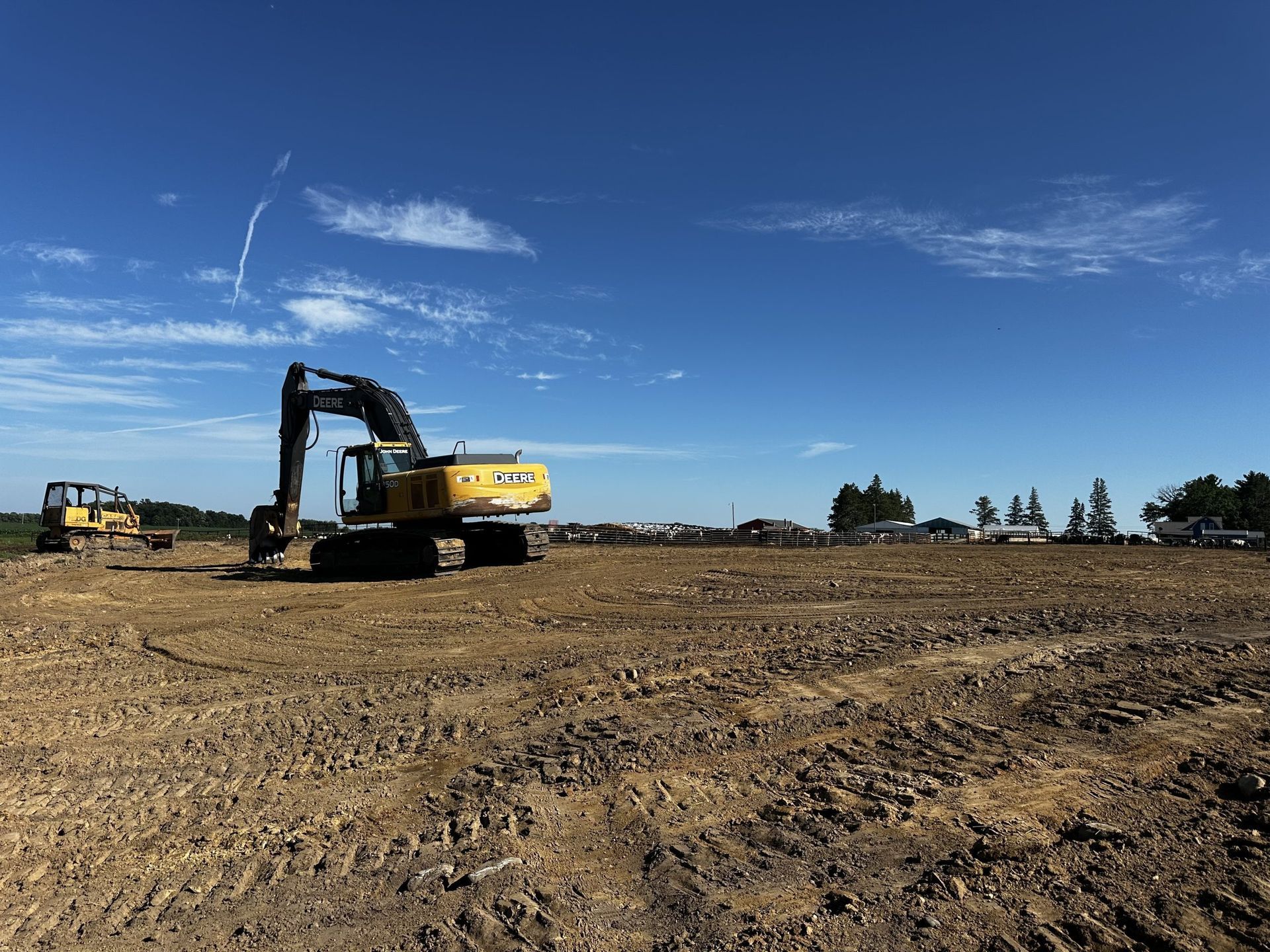 Excavator on a dirt construction site under a clear blue sky.