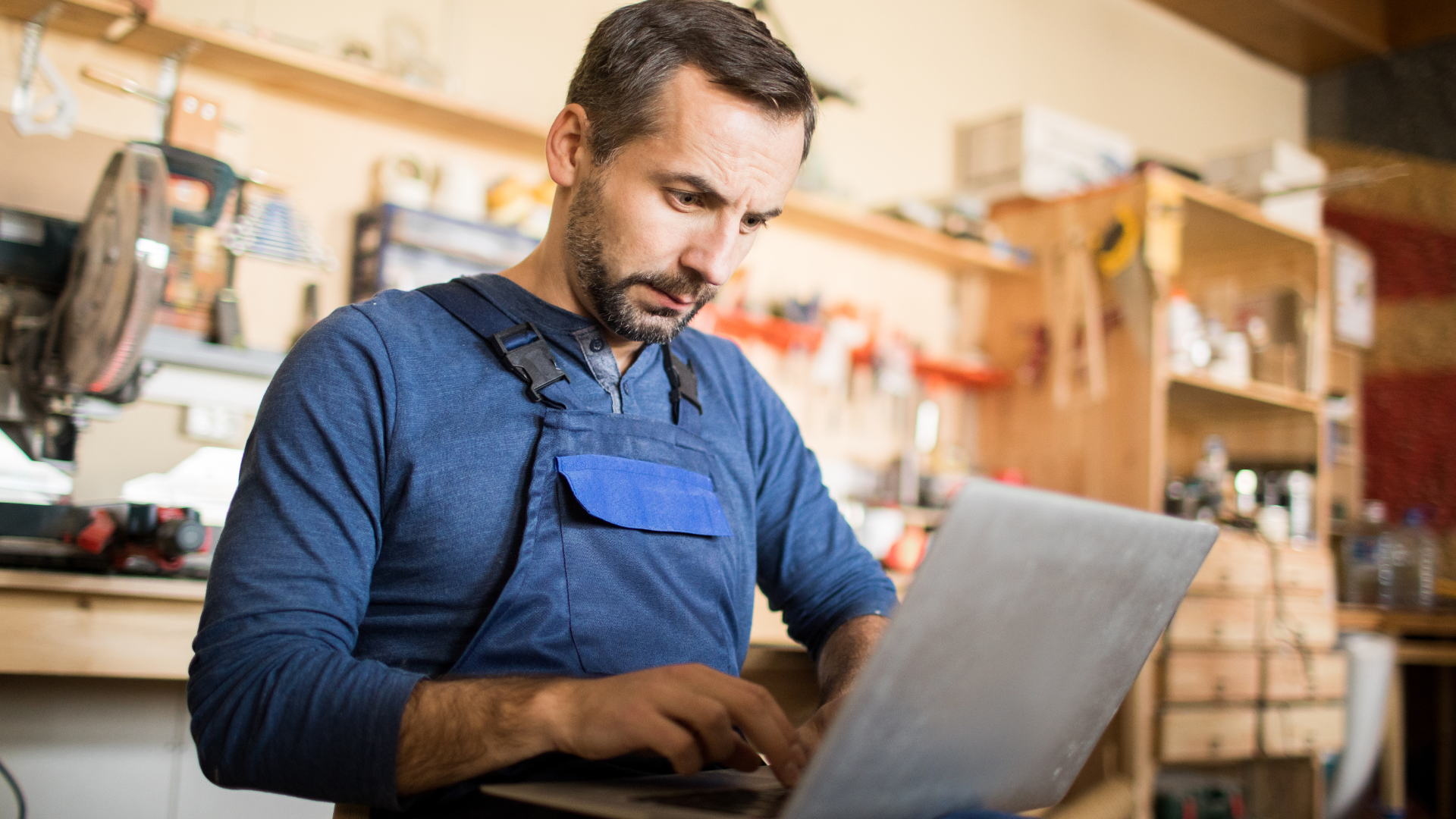 A man in a blue shirt and tie is using a laptop computer.