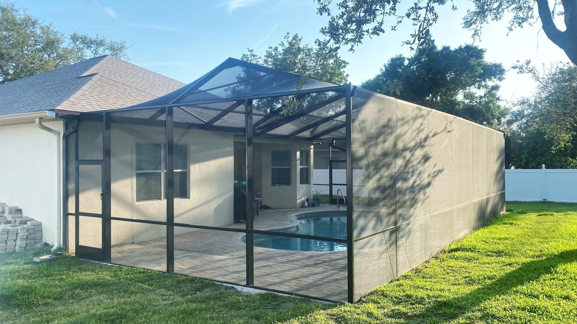 A screened-in pool enclosure attached to a house, with a pool inside.
