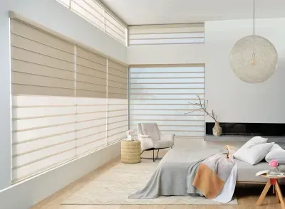 Bright minimalist bedroom with beige blinds, white bed, chair, and large round pendant lamp