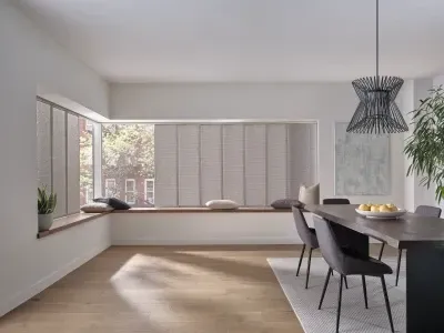 Bright minimalist dining room with large window seat, dark chairs, and a hanging pendant light