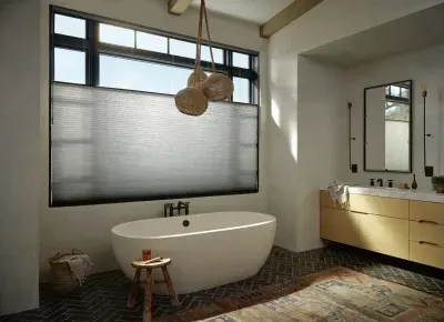 Modern bathroom with freestanding tub, large window, double vanity, and woven light fixture