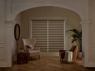 Cozy living room with arched doorway, beige armchair, potted plant, and shuttered window