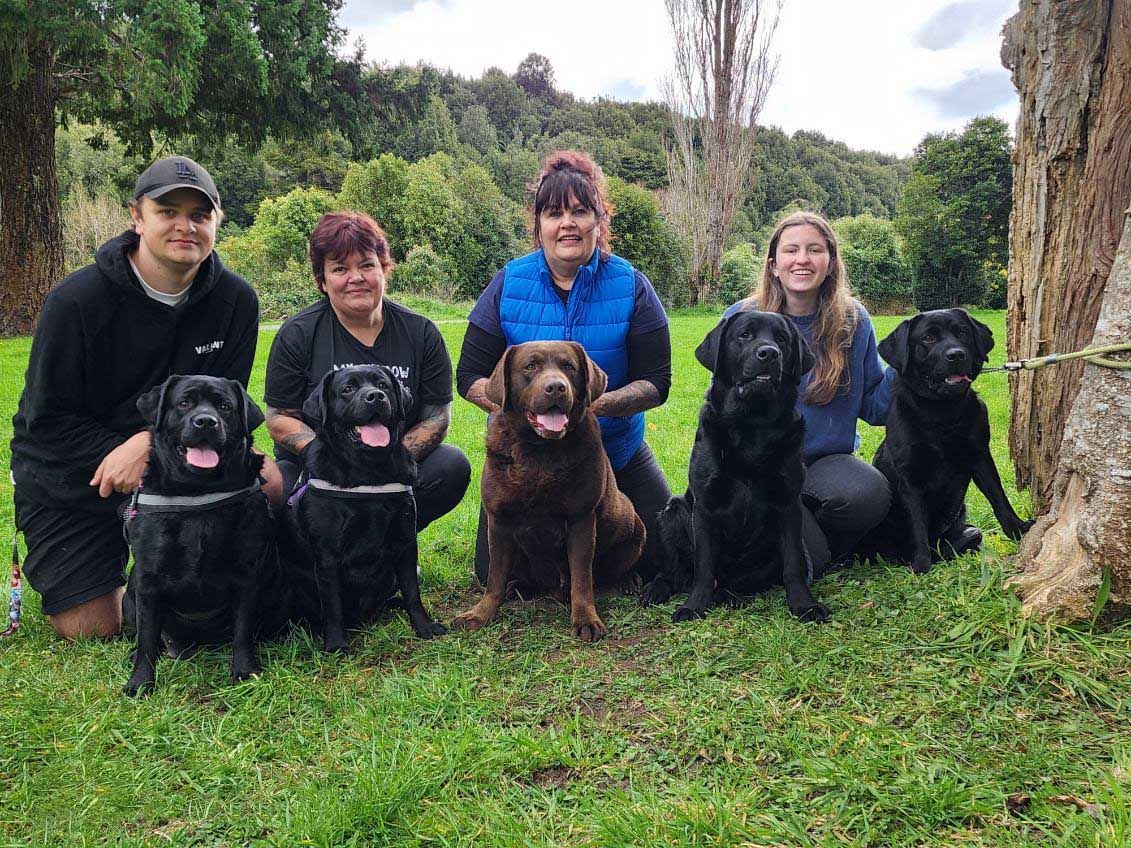A group of people are posing for a picture with their dogs.