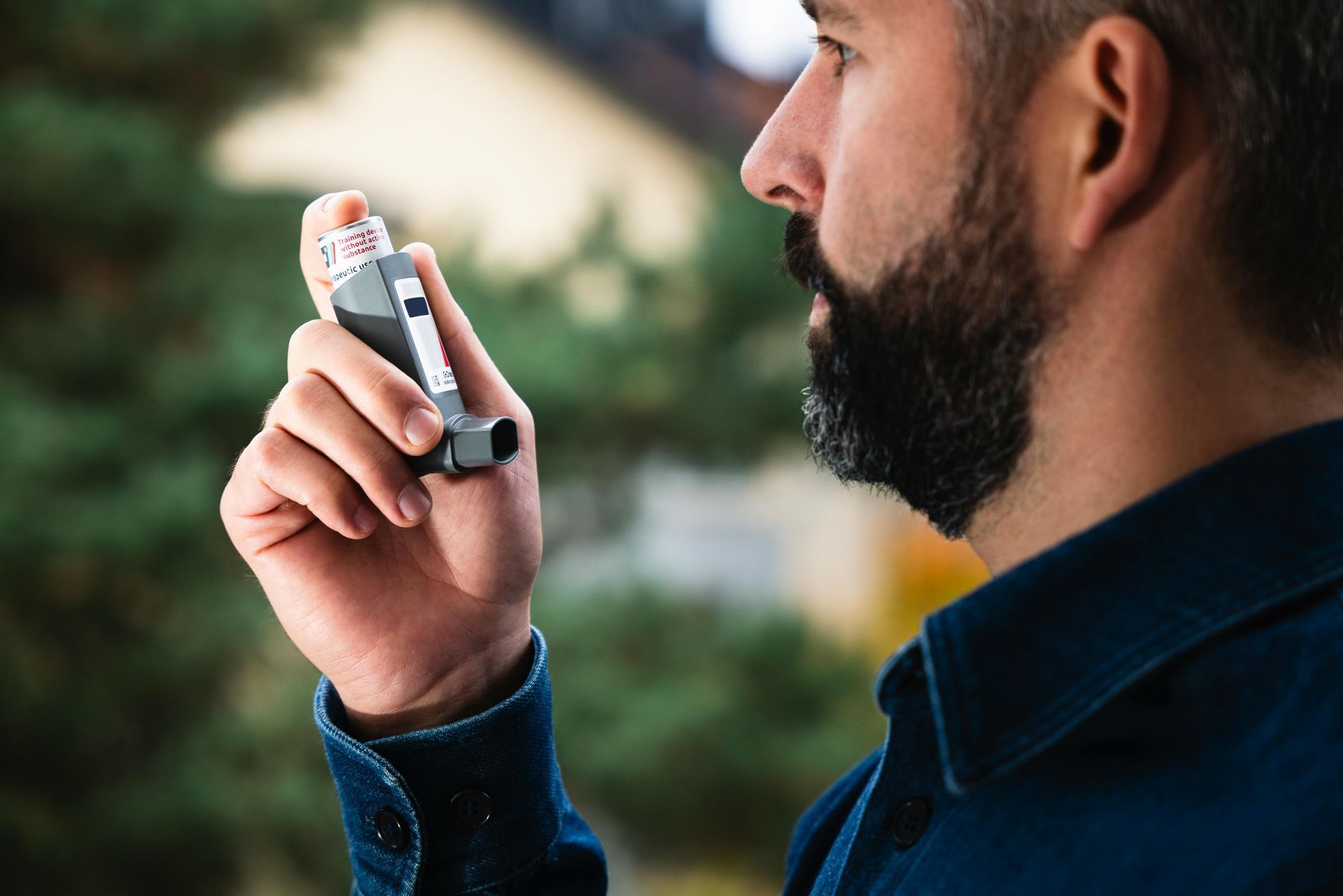A man with a beard is holding an inhaler in his hand.