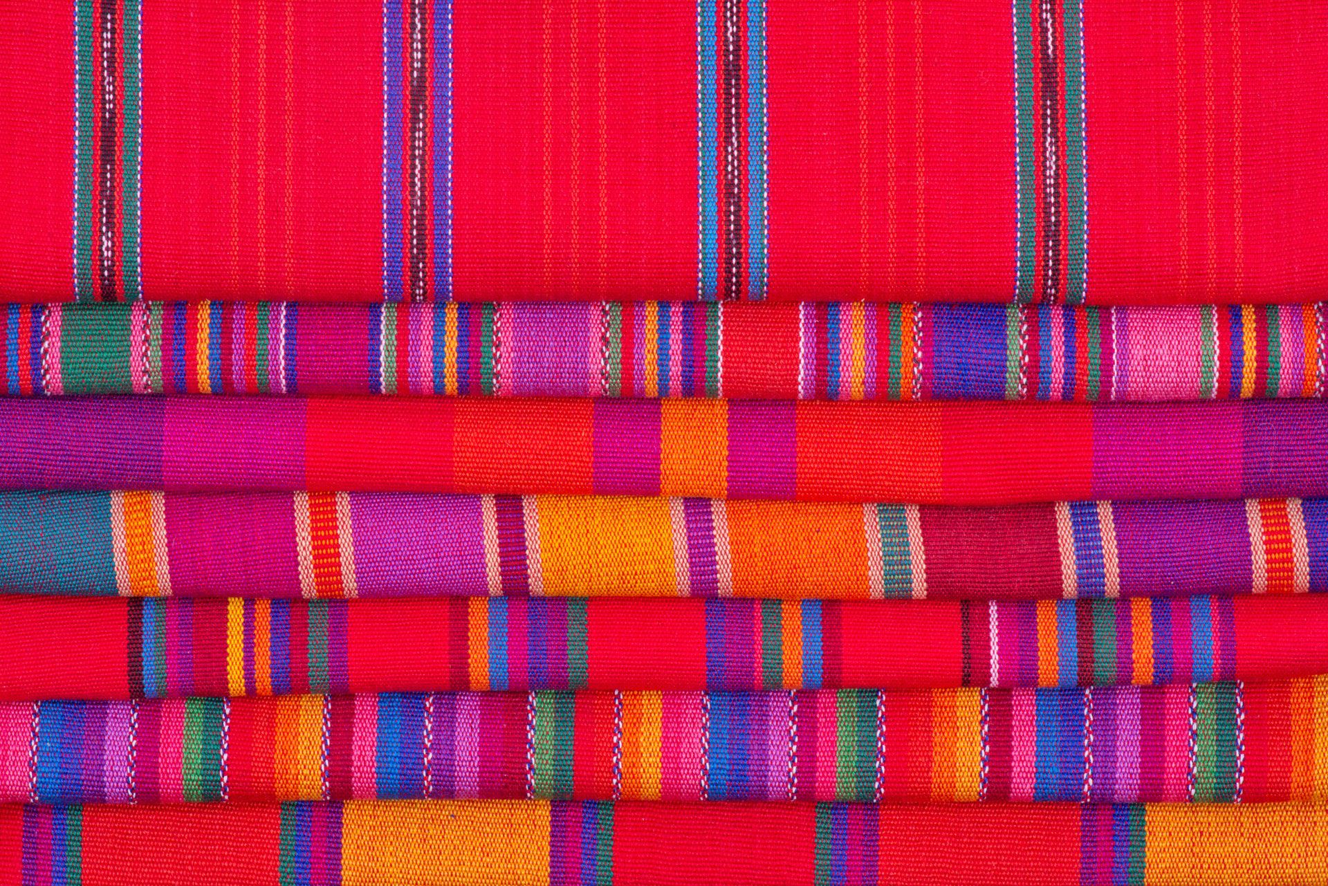 Tessuti colorati intrecciati, impilati, con strisce rosse, viola, arancioni, blu e verdi.