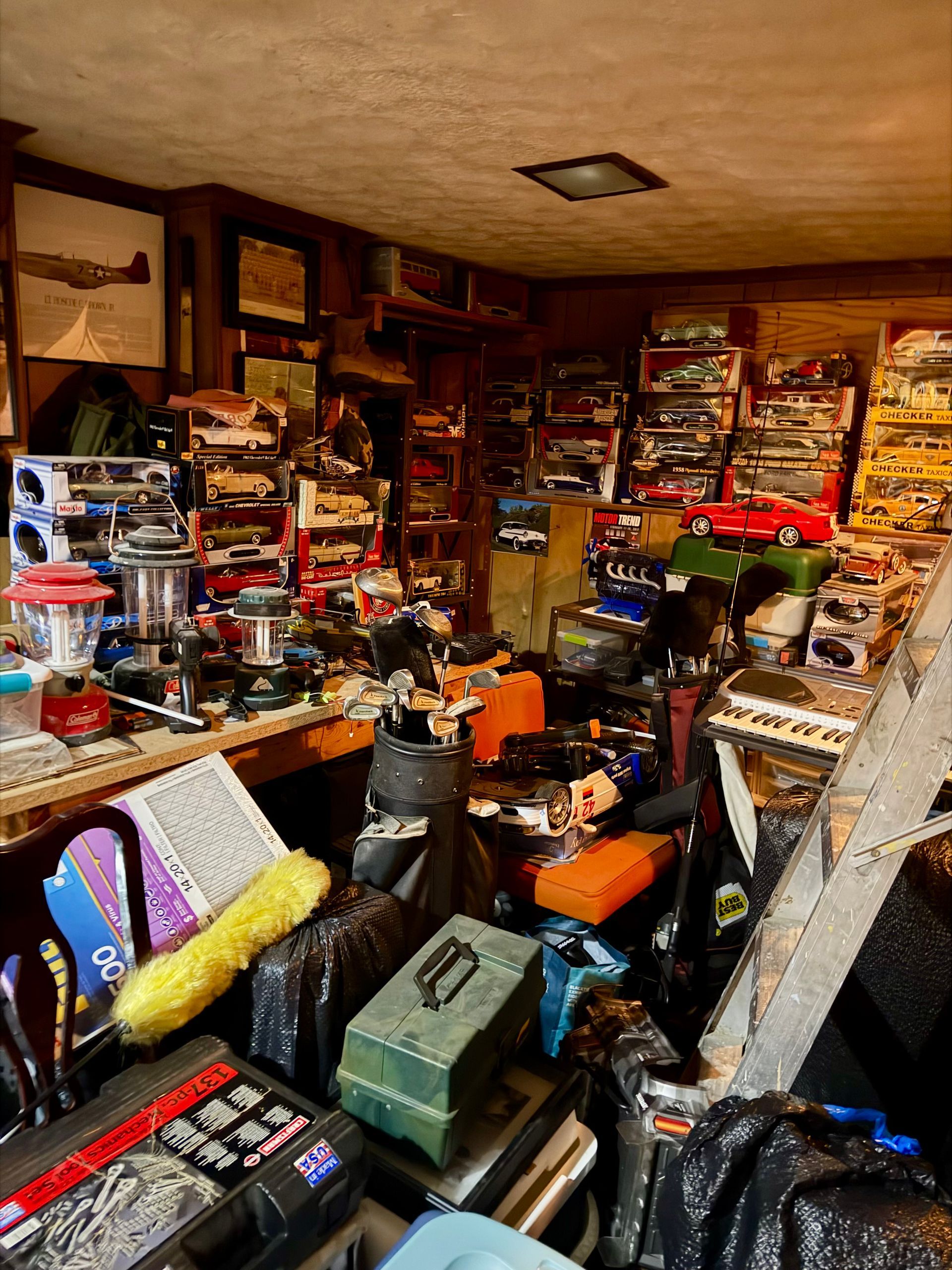 Cluttered basement workshop with tools, die-cast cards, and packed storage items before listing.