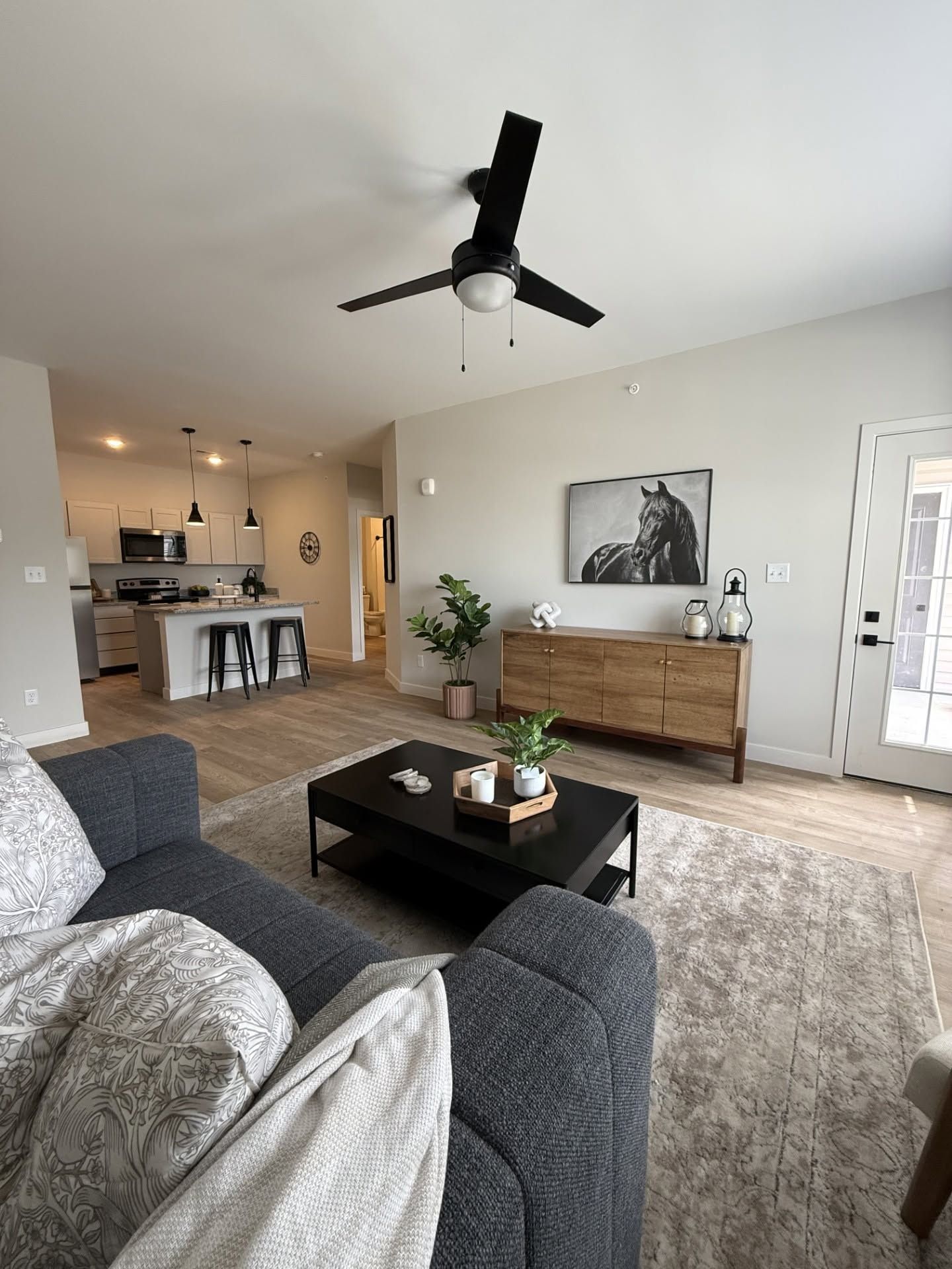 Modern living room and kitchen in a new‑construction apartment featuring neutral décor, stainless ap