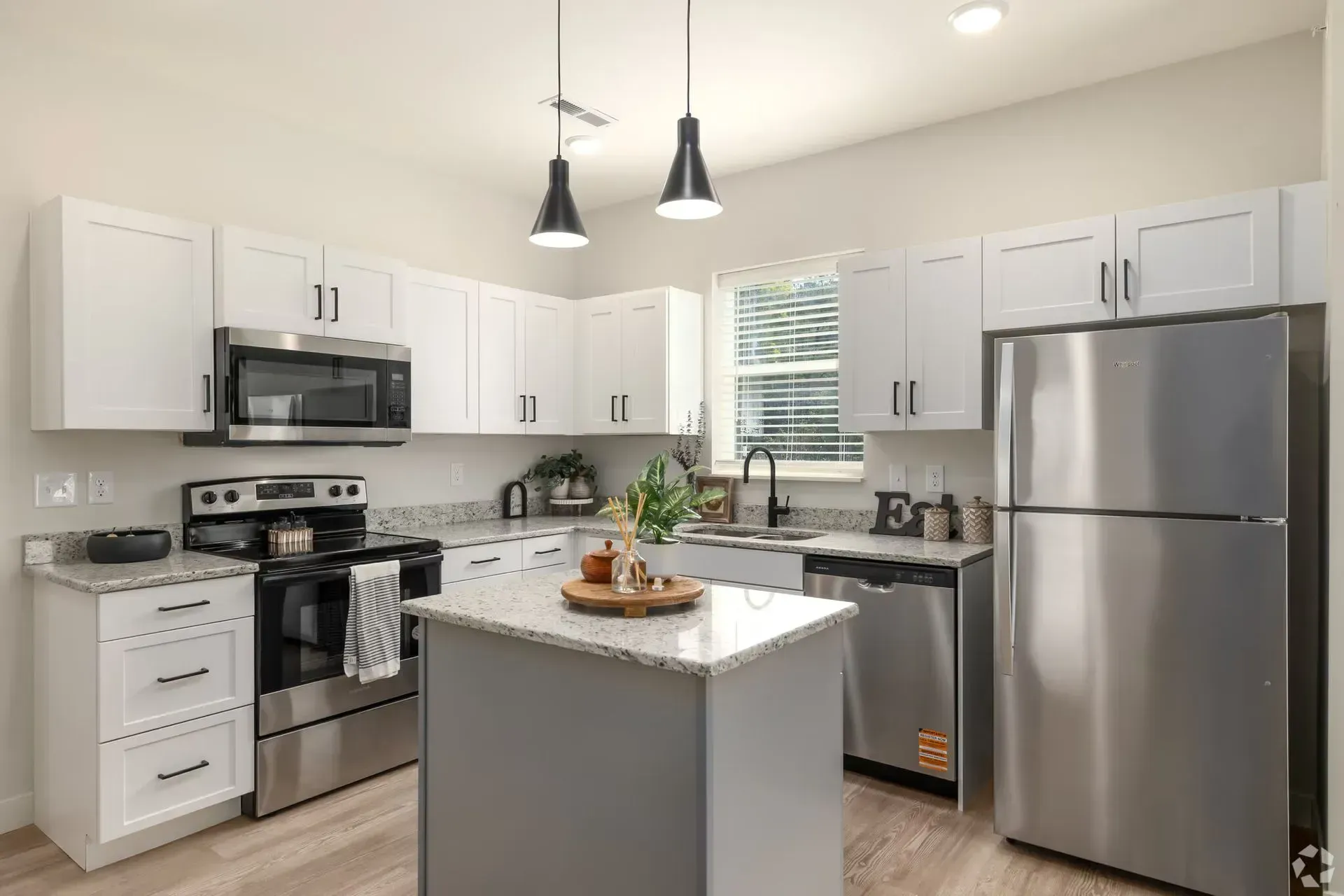 Modern kitchen in Millcreek apartment featuring stainless steel appliances, white cabinetry, granite