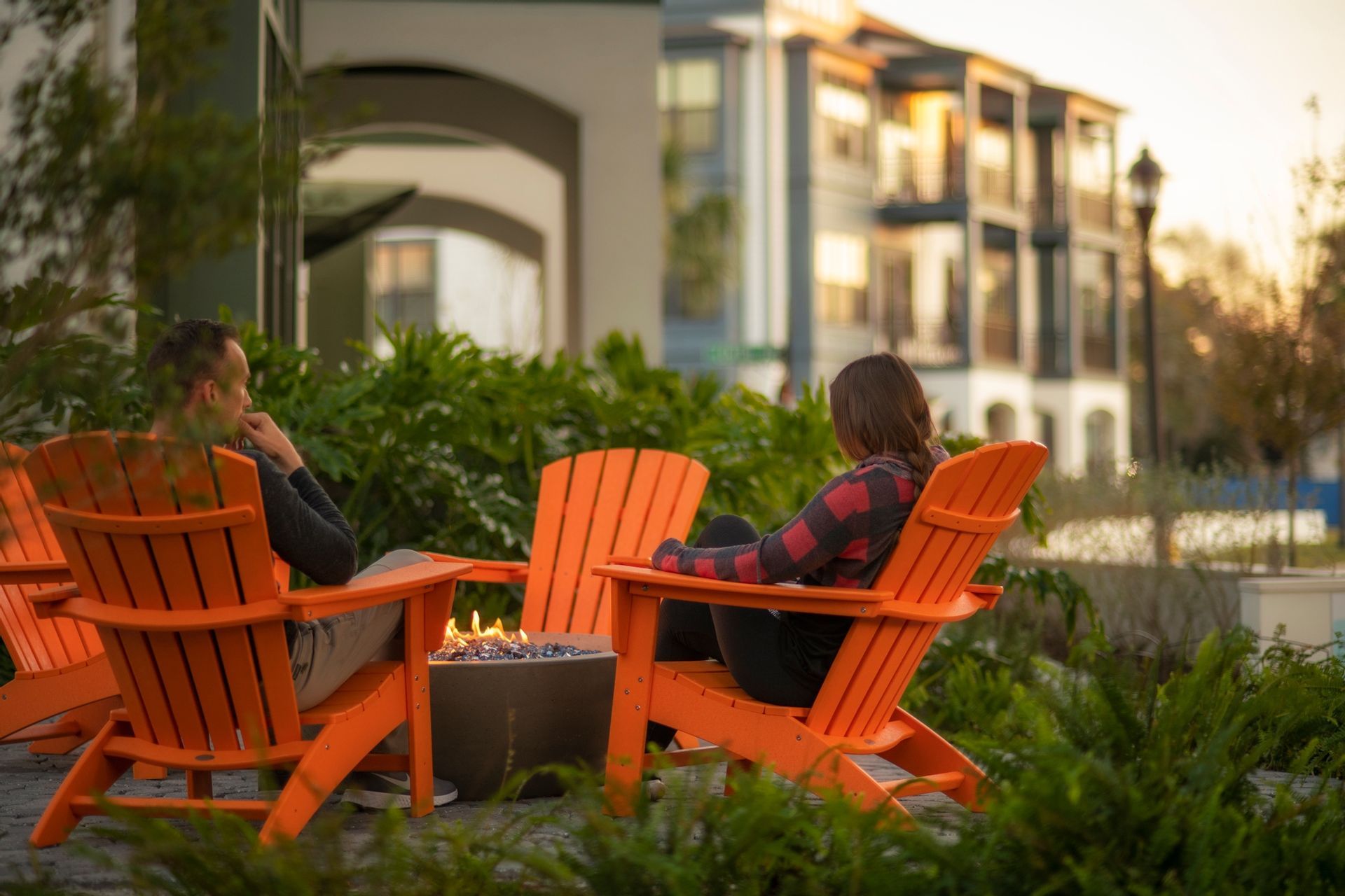 Photo showing two people sitting in outdoor chairs next to a firepit