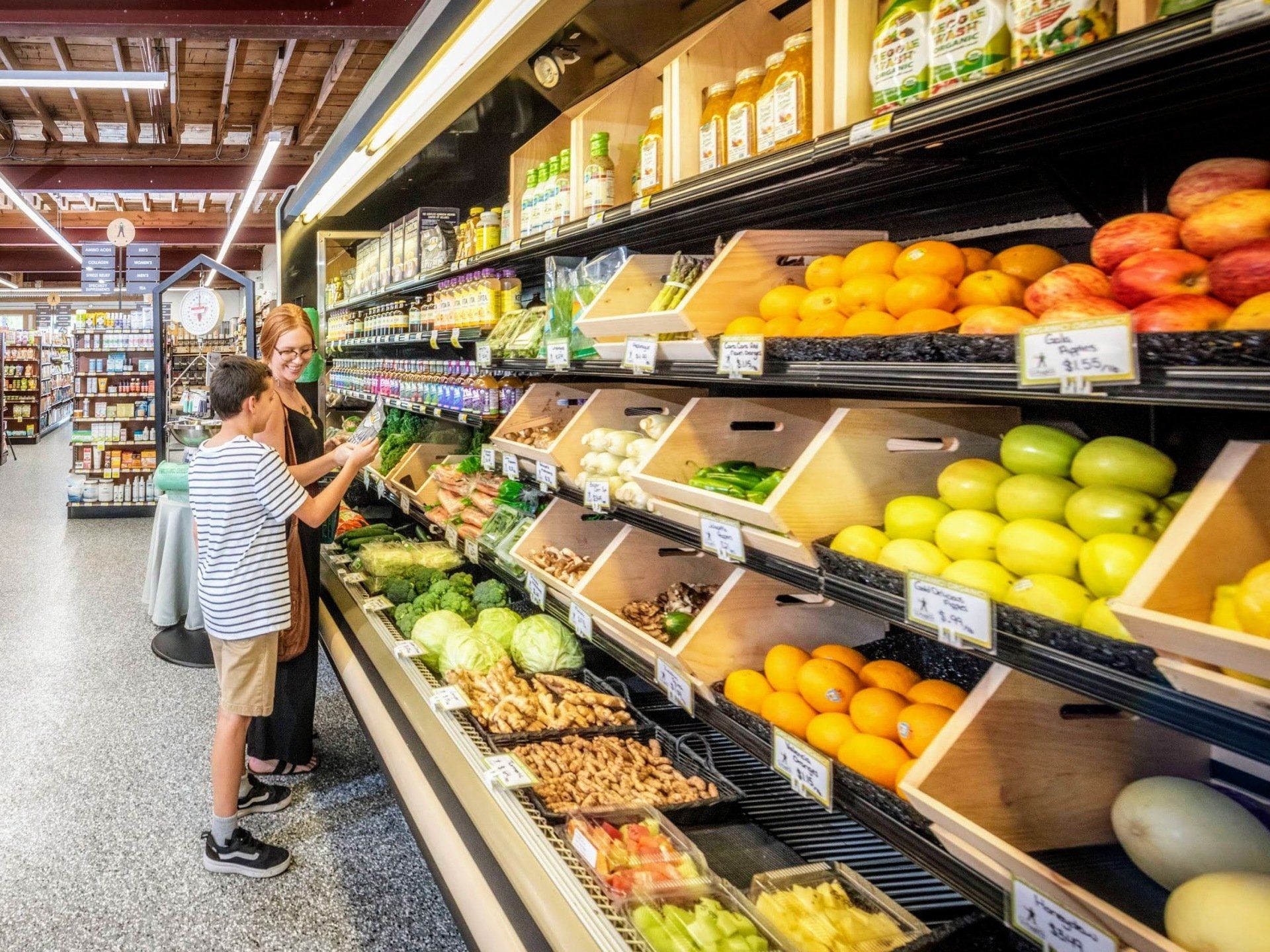 A fruit section in the grocery store, with people standing in the distance