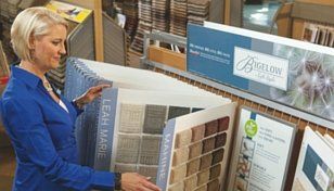 Woman in blue jacket browsing a fabric sample display in a store showroom