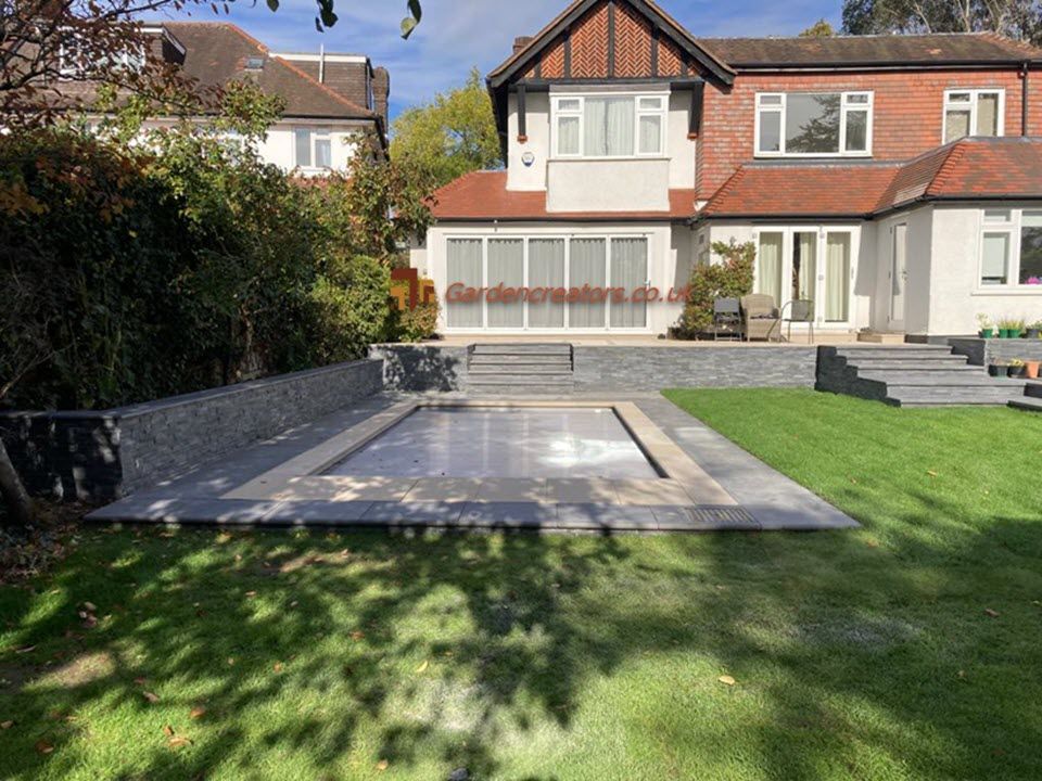 A large house with a large swimming pool in front of it, composite deck and stone paving patio