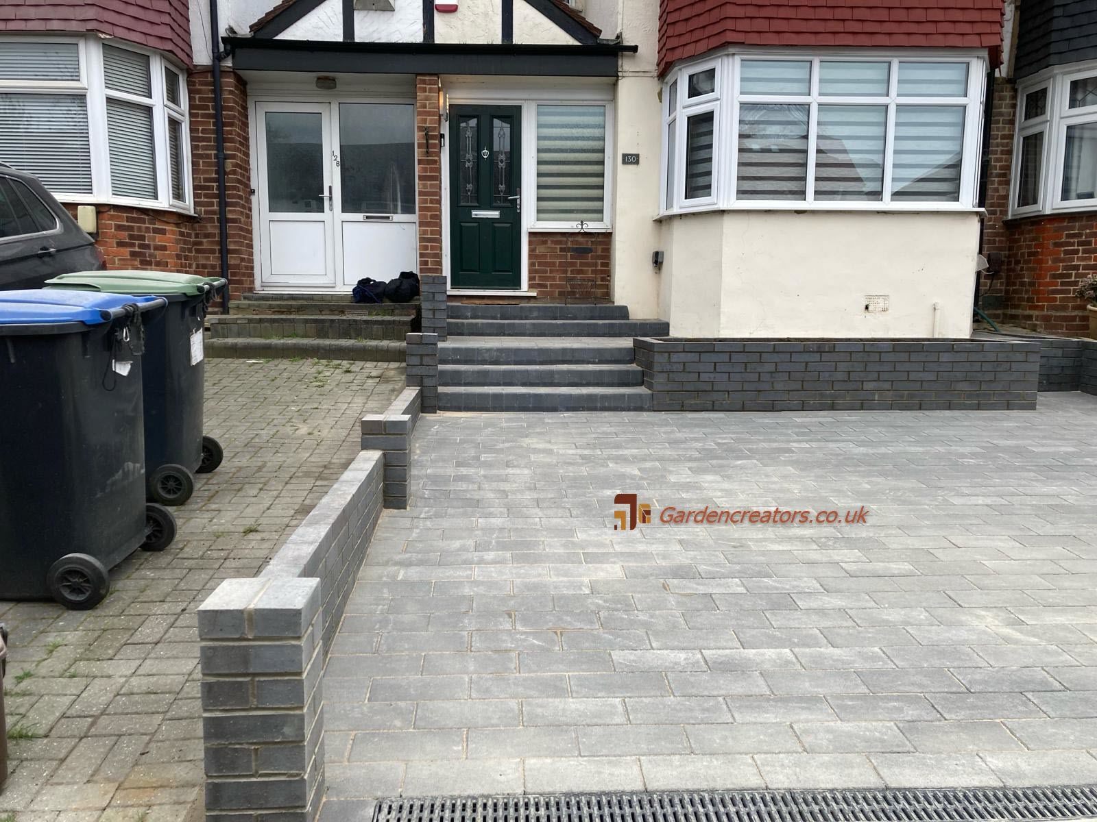 A house with a brick driveway and stairs in front of it.