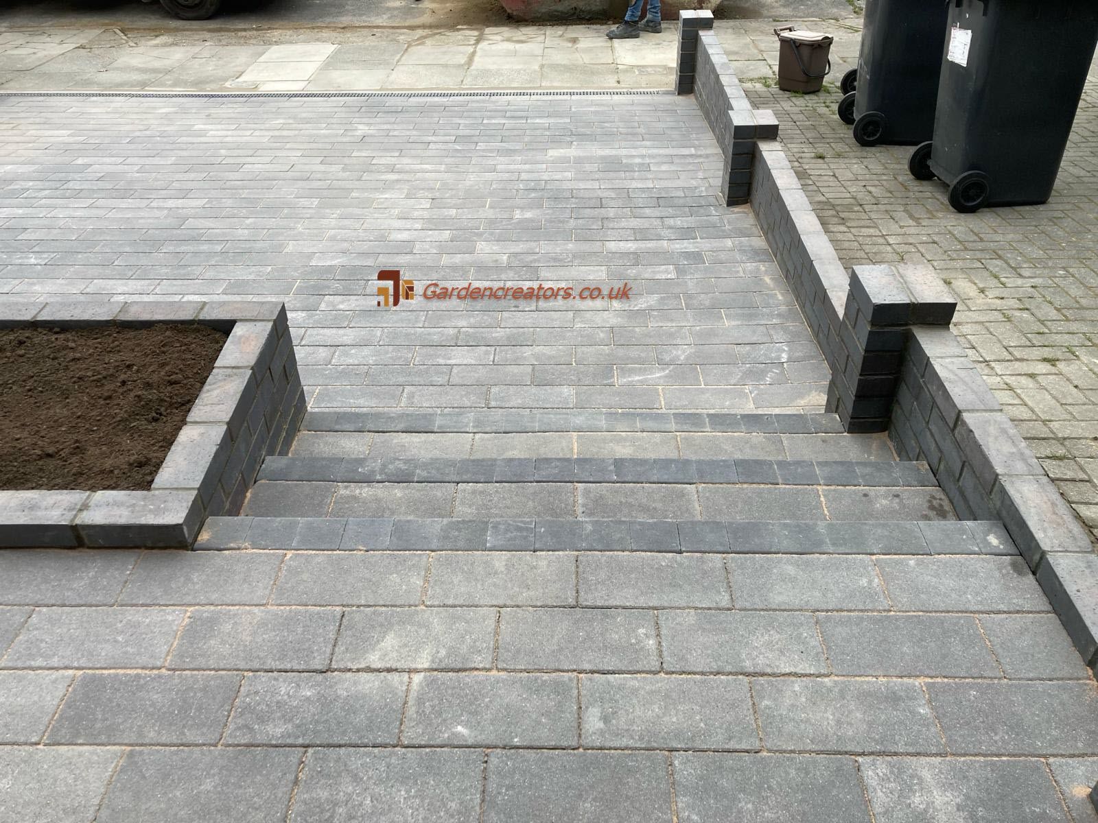 A set of stairs leading up to a brick driveway.