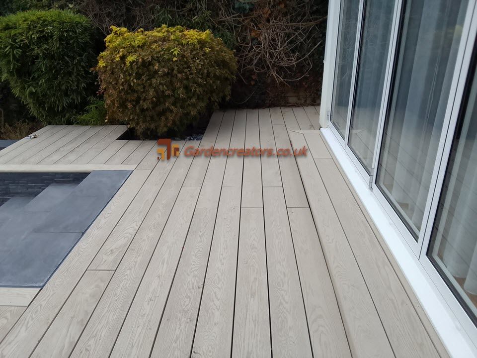 A composite deck patio with a sliding glass door in the background