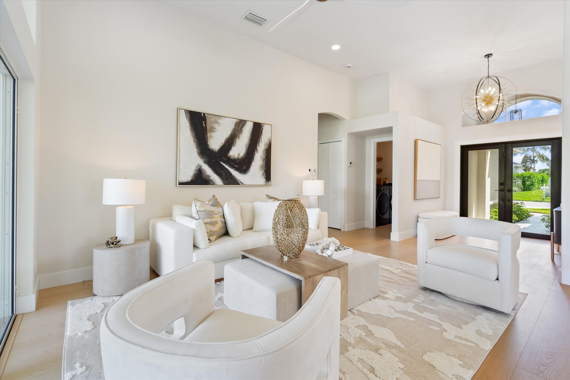 A living room with white furniture and a painting on the wall
