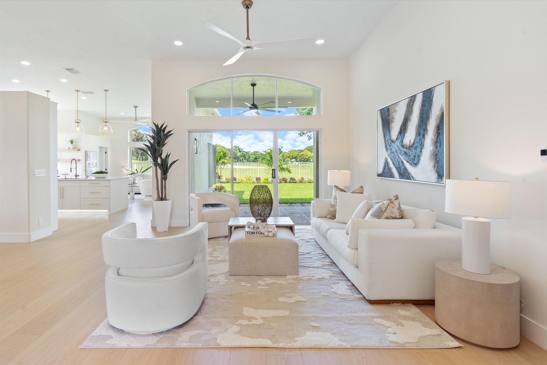 A living room with white furniture and a ceiling fan.