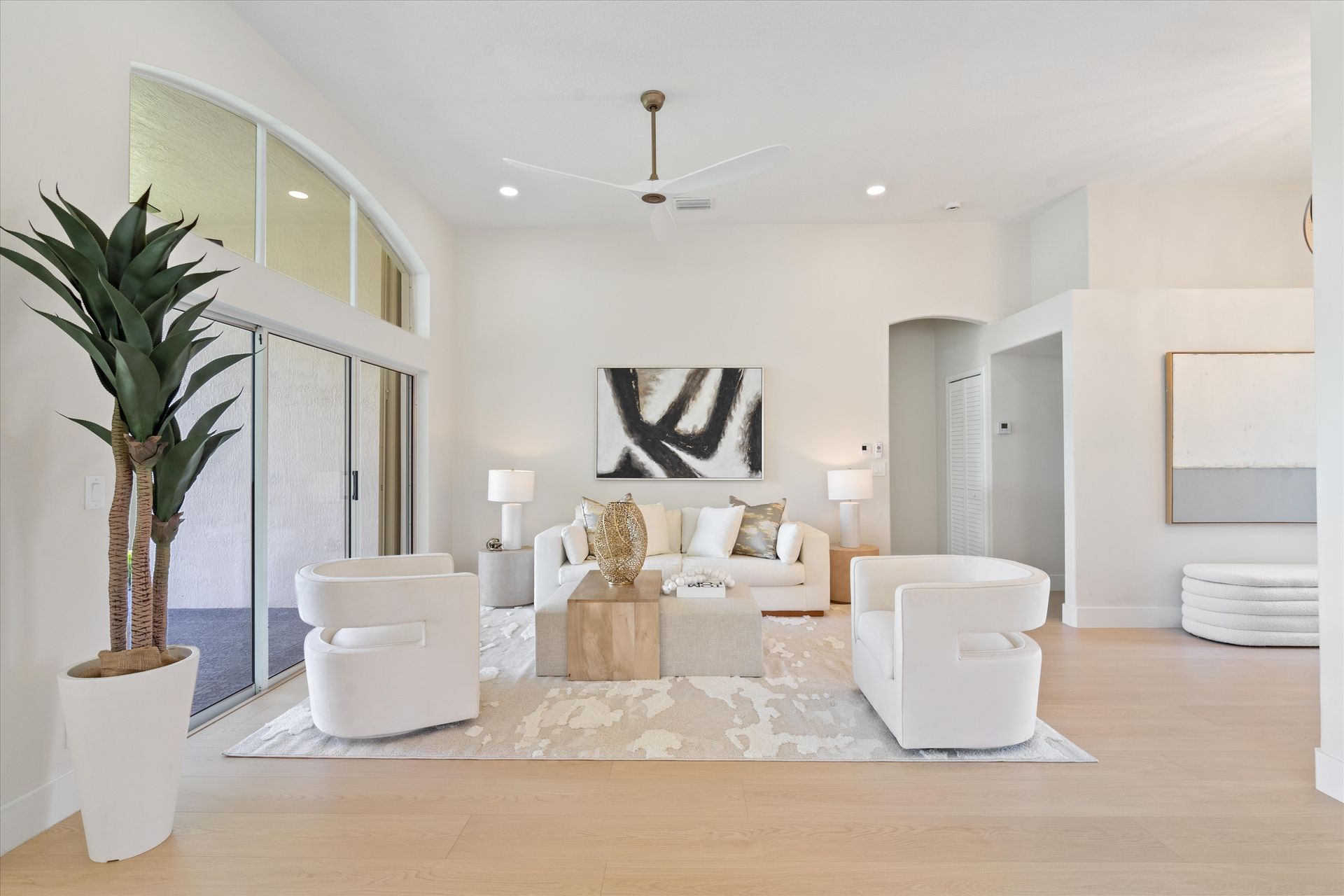 A living room with white furniture and a ceiling fan.