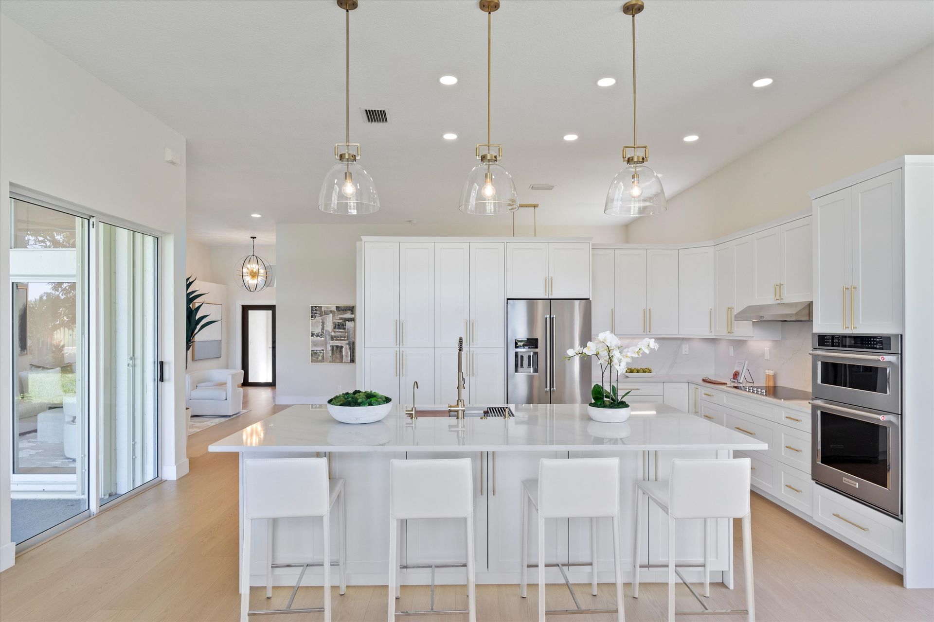 A kitchen with white cabinets , stainless steel appliances , and a large island.