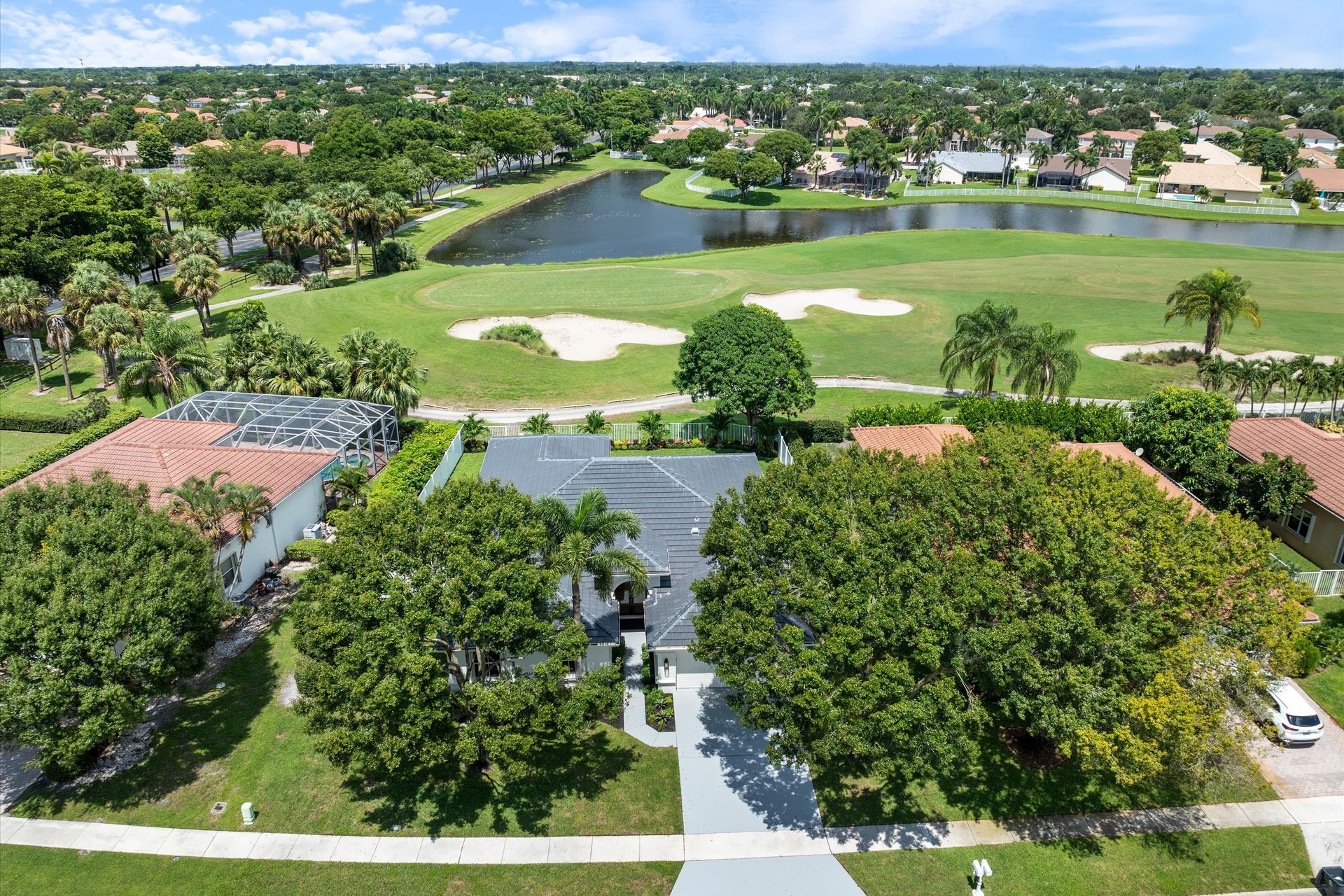 An aerial view of a house and a golf course in a residential area.