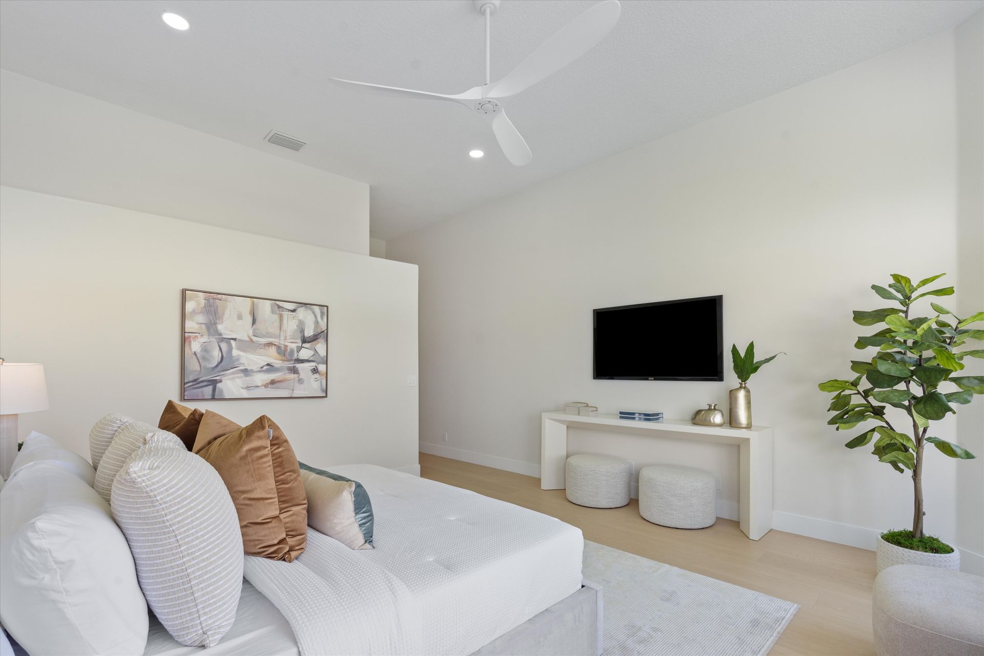 A bedroom with a large bed and a flat screen tv on the wall.