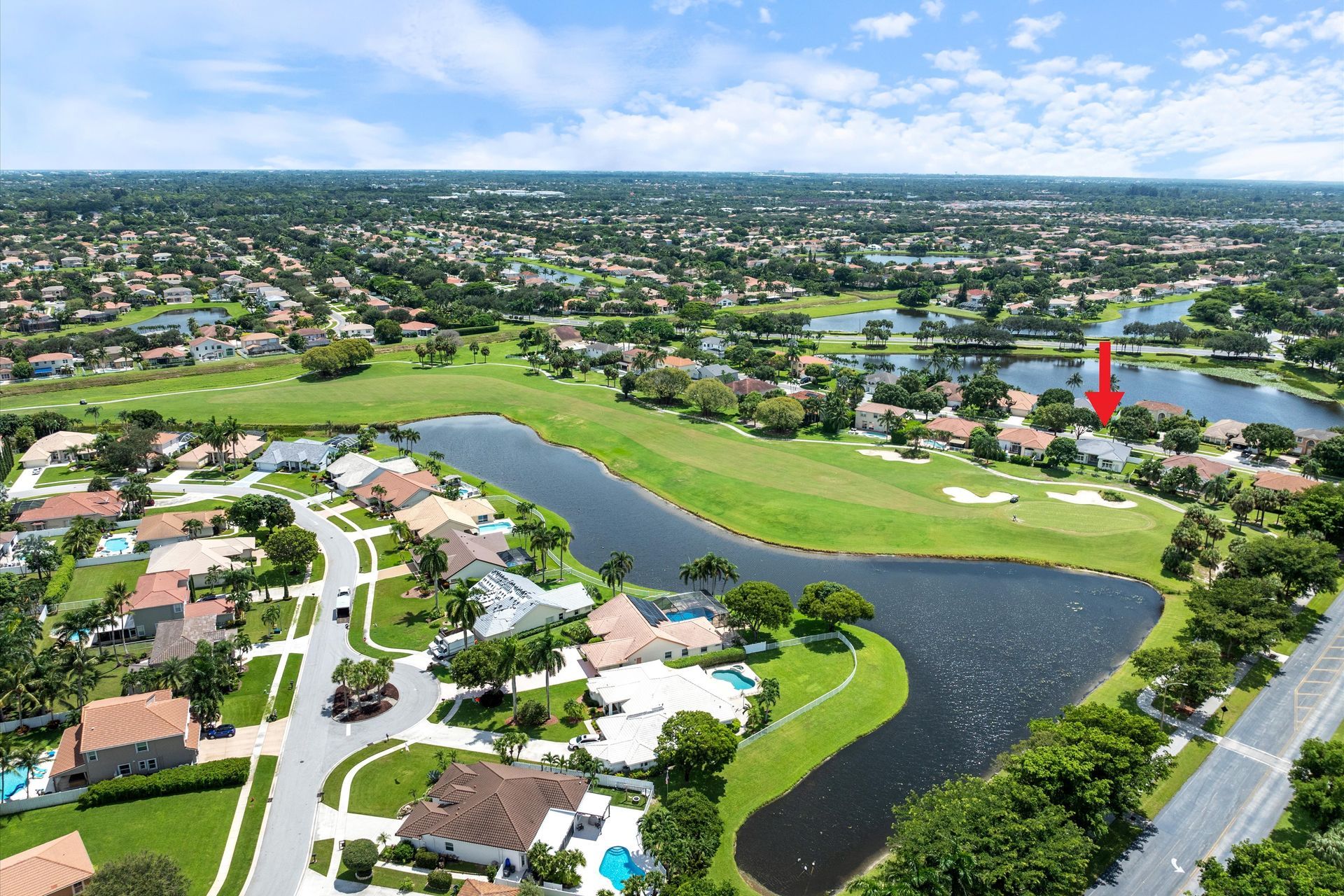 An aerial view of a residential area with a red arrow pointing to a house
