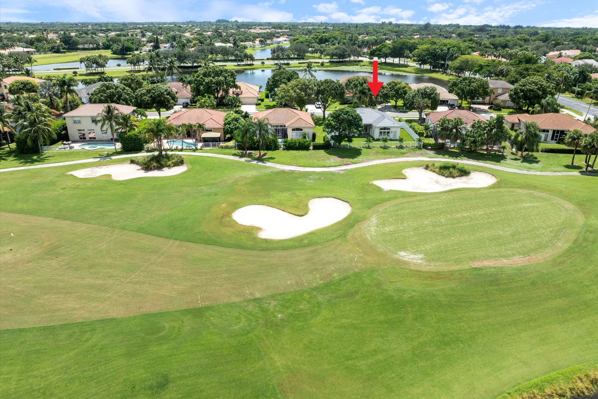 An aerial view of a golf course with houses in the background