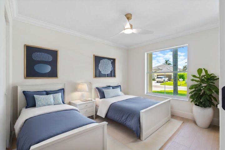 A bedroom with two beds , a window and a ceiling fan.
