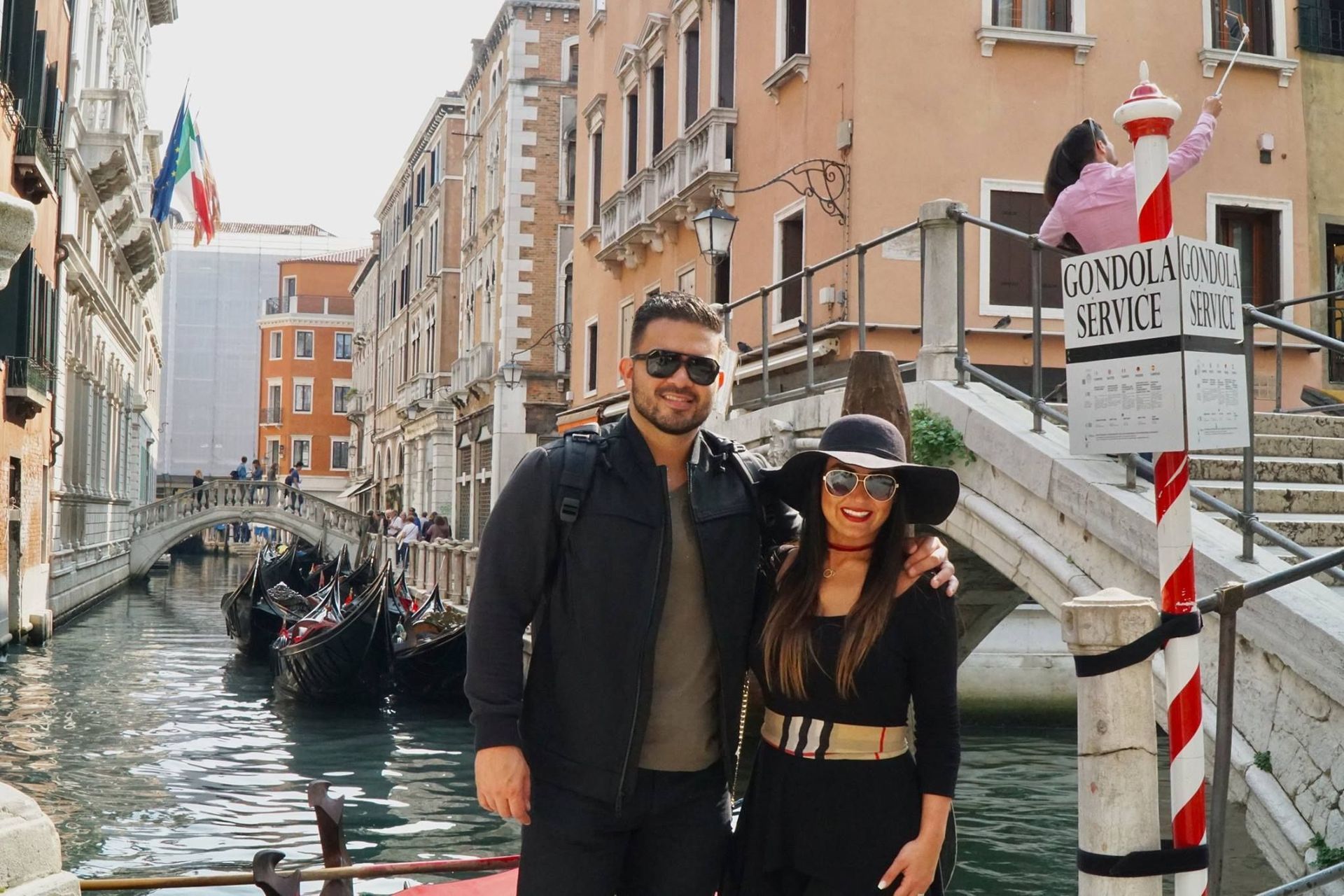 A man and a woman are posing for a picture in front of a canal in venice.