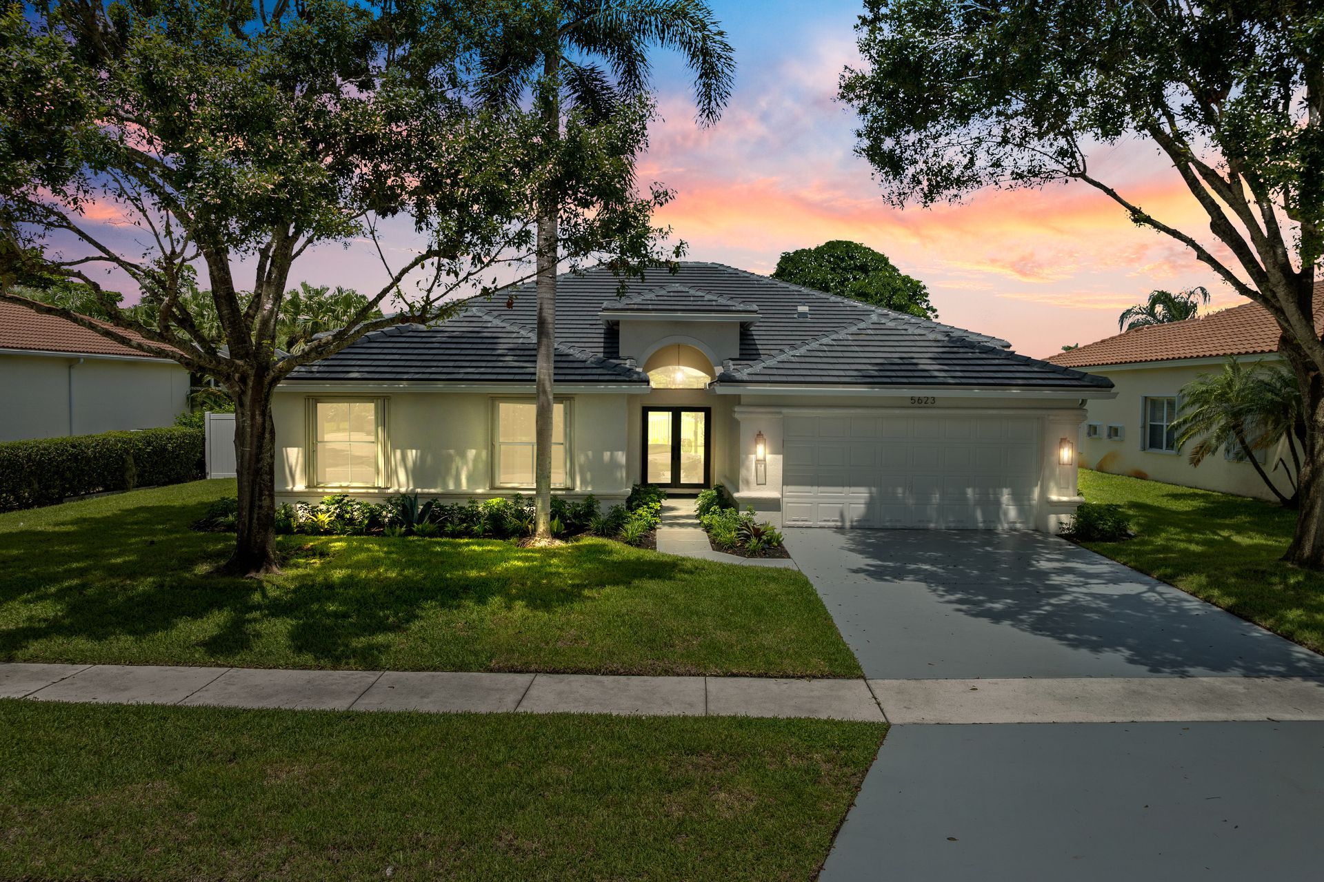 A white house with a sunset in the background is for sale.
