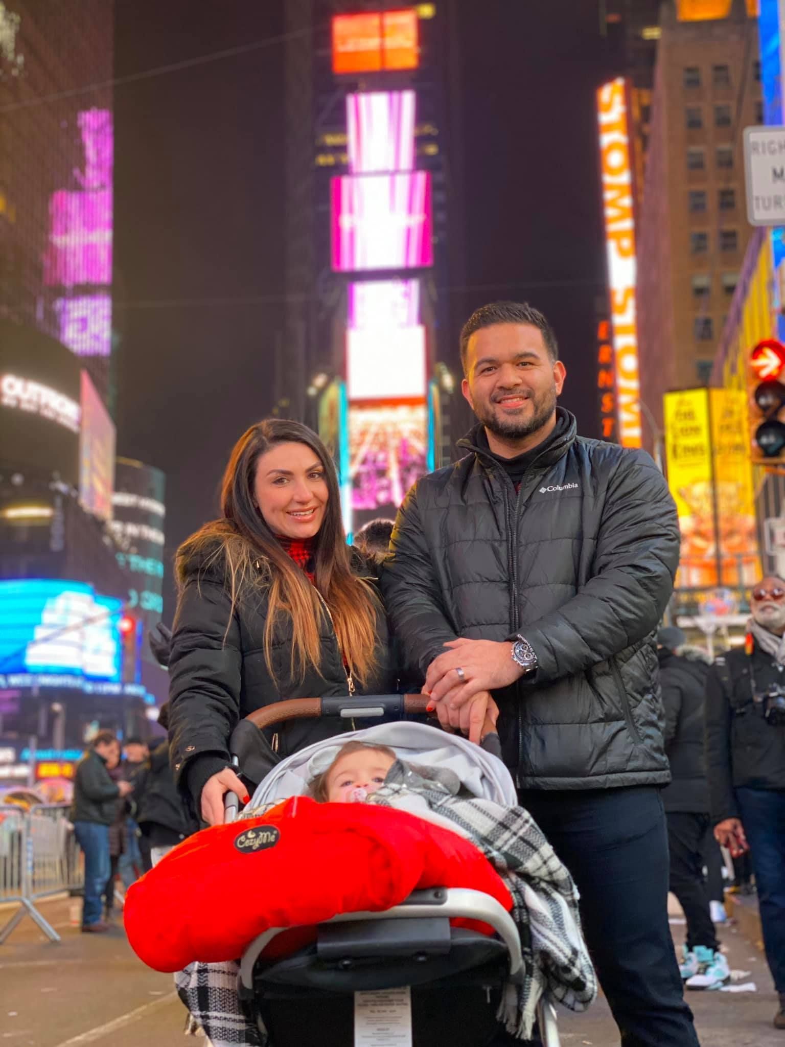 A man and a woman are standing next to a baby in a stroller.