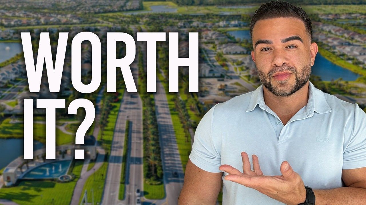 Man in light blue shirt gesturing beside bold text “WORTH IT?” over a blurred aerial cityscape