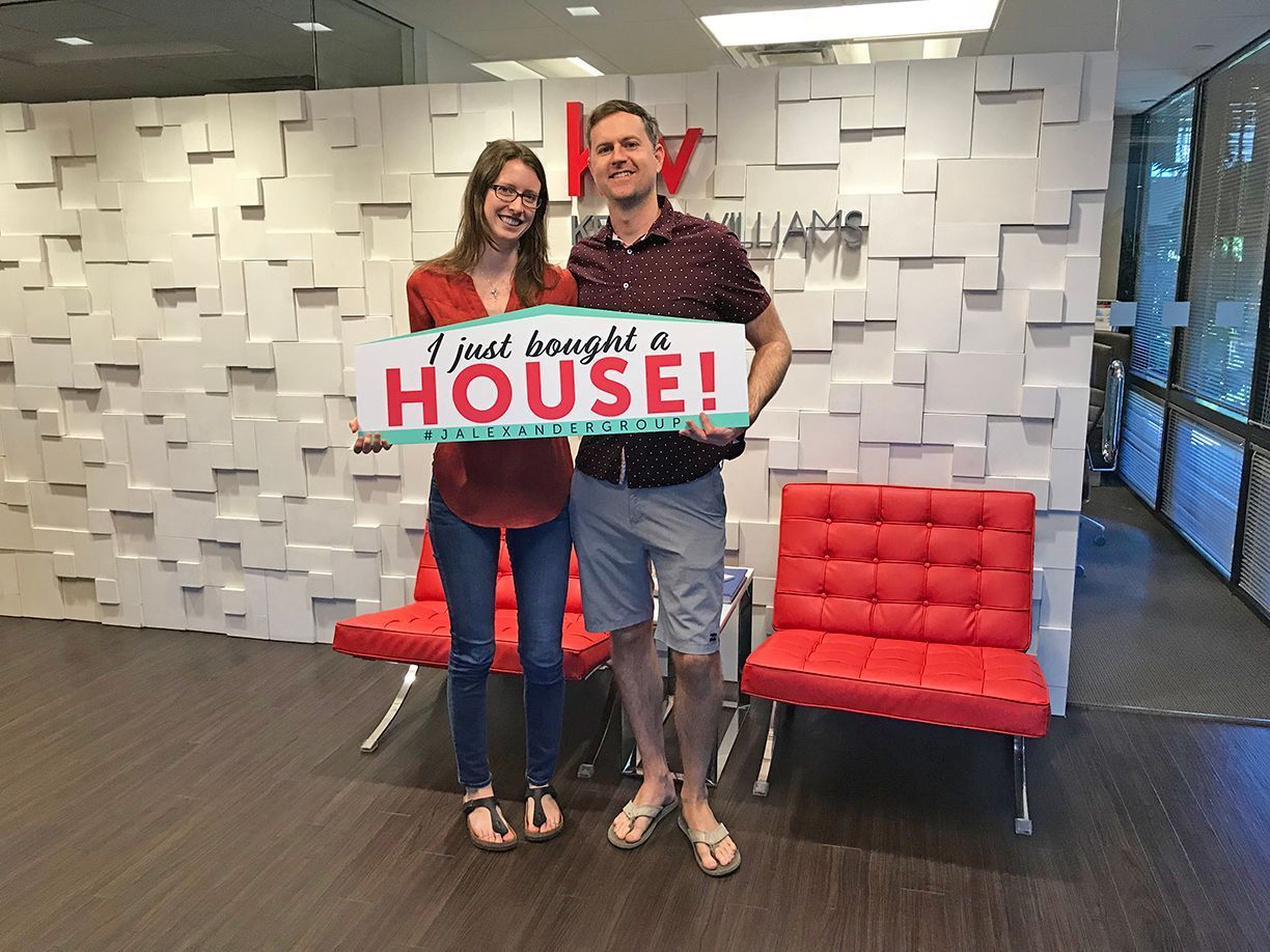 A man and a woman are holding a sign that says `` i just bought a house ''.