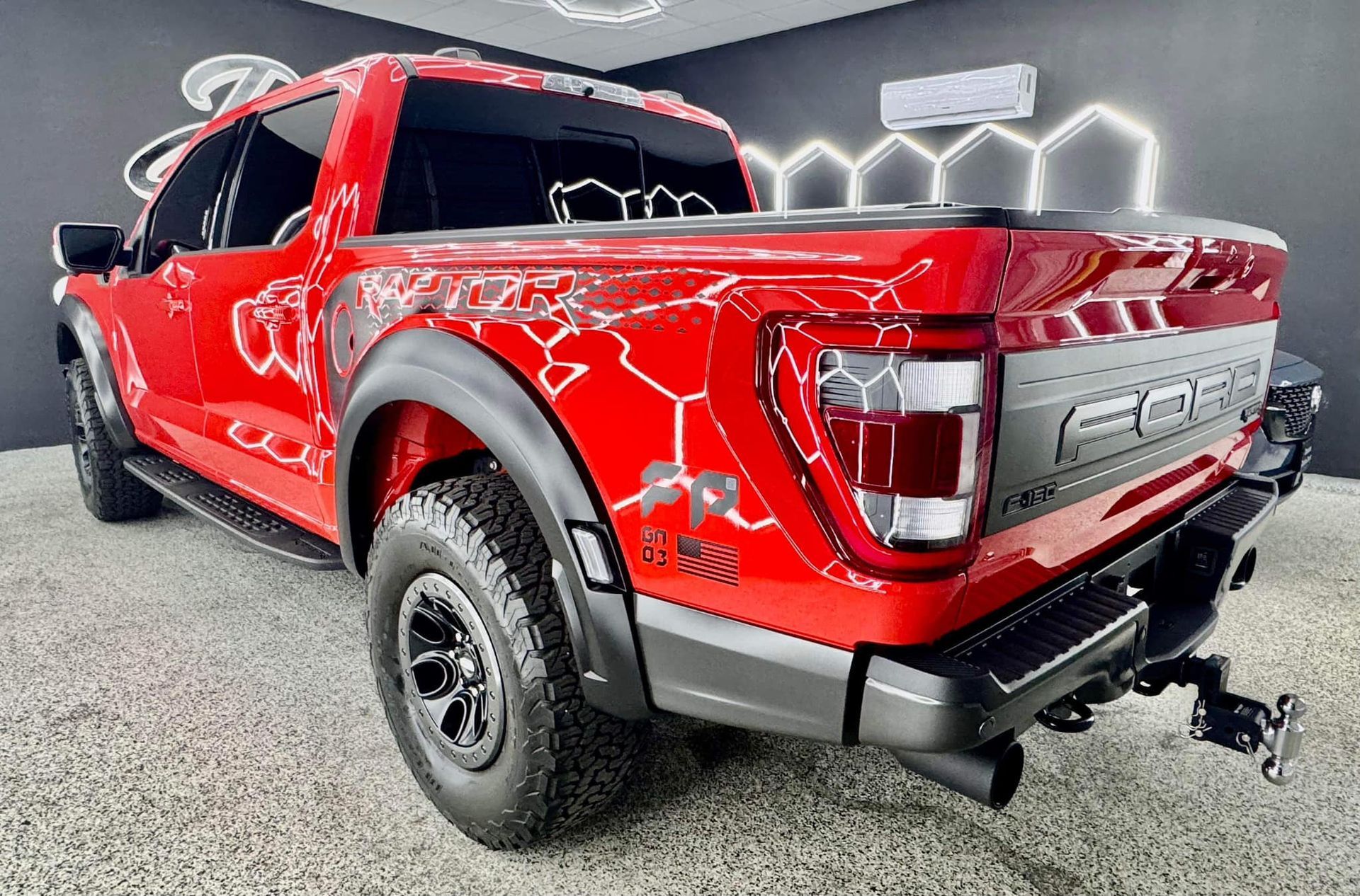 A red ford raptor truck is parked in a showroom.