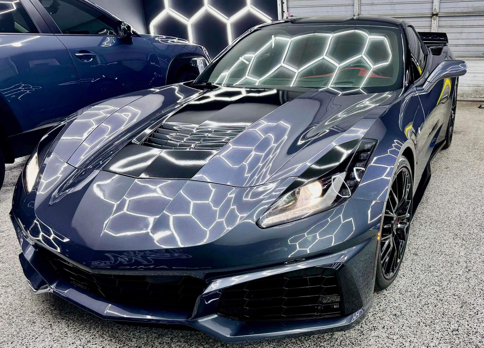A black sports car is parked in front of a garage.