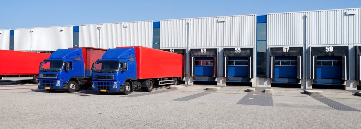 A row of trucks are parked in front of a warehouse.