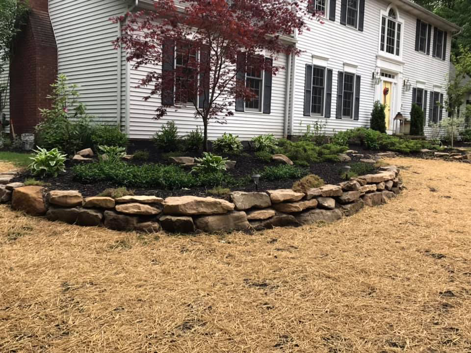a large white house with a stone wall in front of it .
