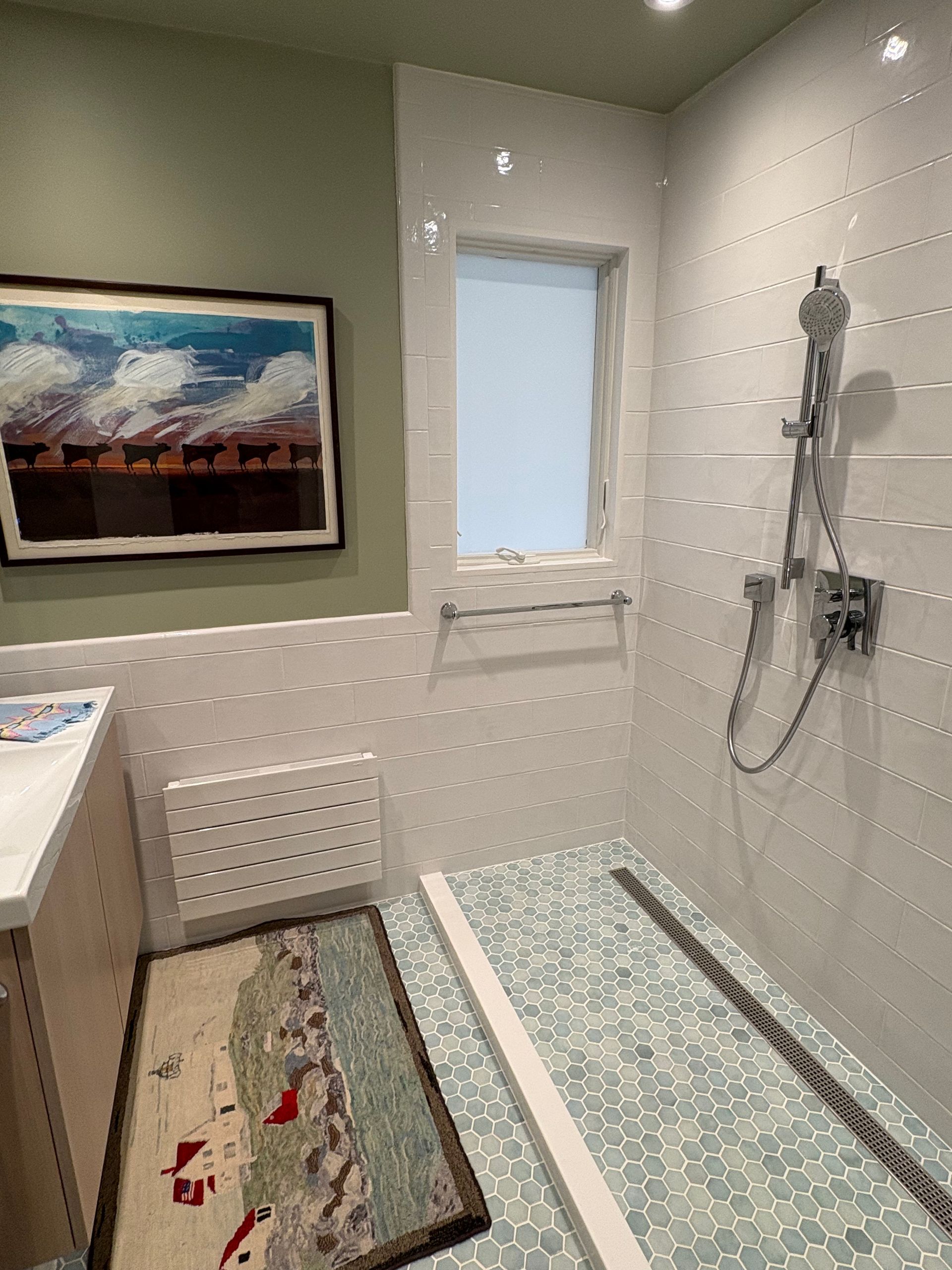 Modern bathroom with tiled shower, window, wall art, and patterned rug