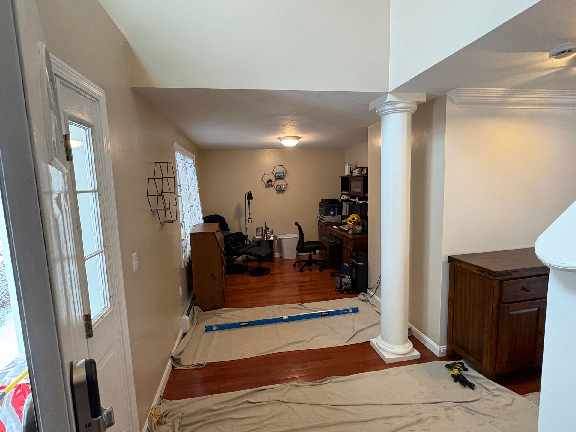 Living room view from front entry, with white columns, hardwood floor, rug, and furniture in the back.