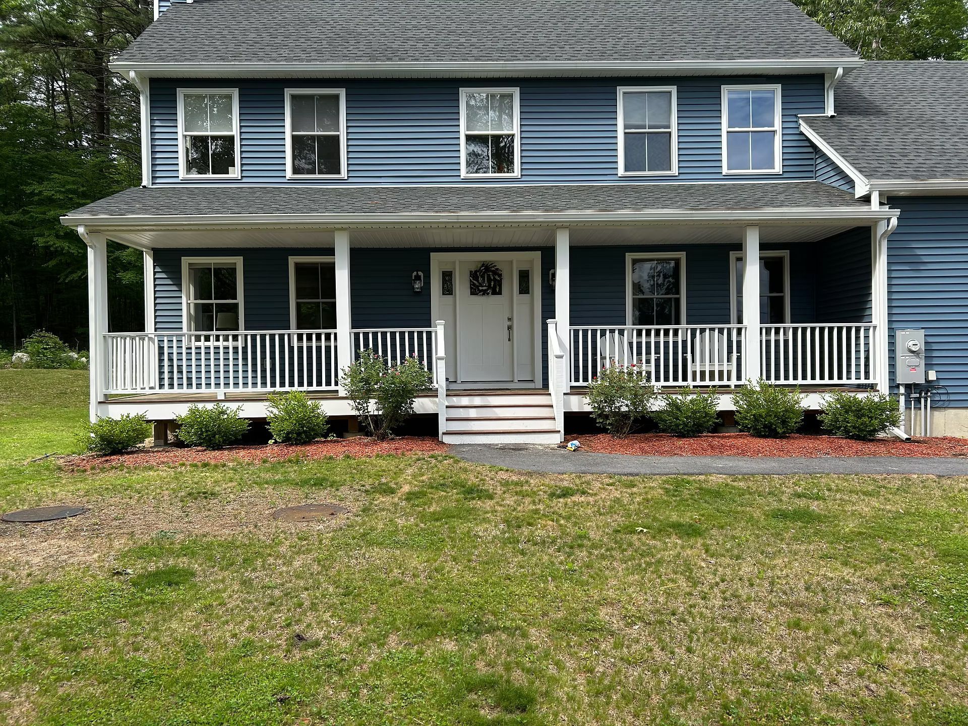 Blue two-story house with a front porch, white trim, and a grassy yard